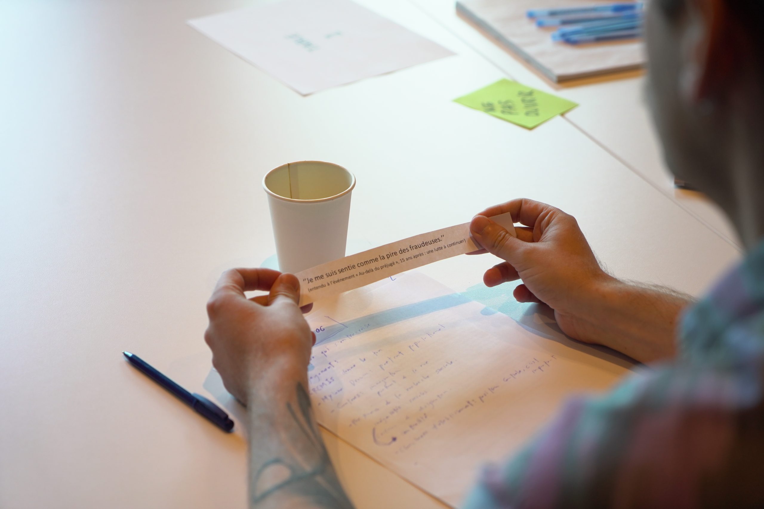 Un participant, de dos, lit un petit papier contenant du texte qu'il tient dans ses mains.